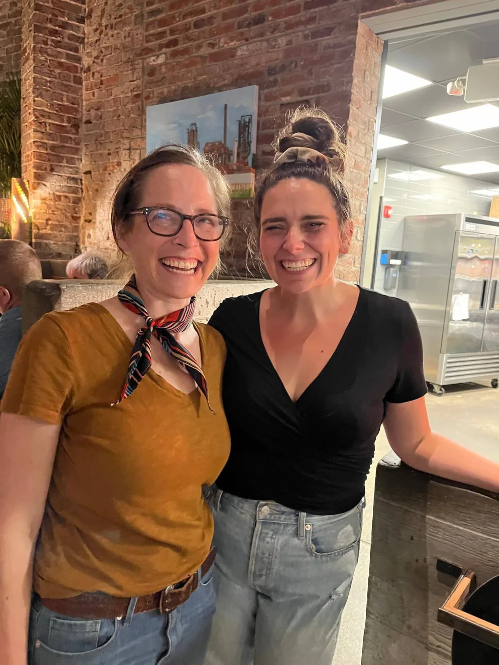 Sarah Walsh and a CDA team member smiling in the brick-walled café