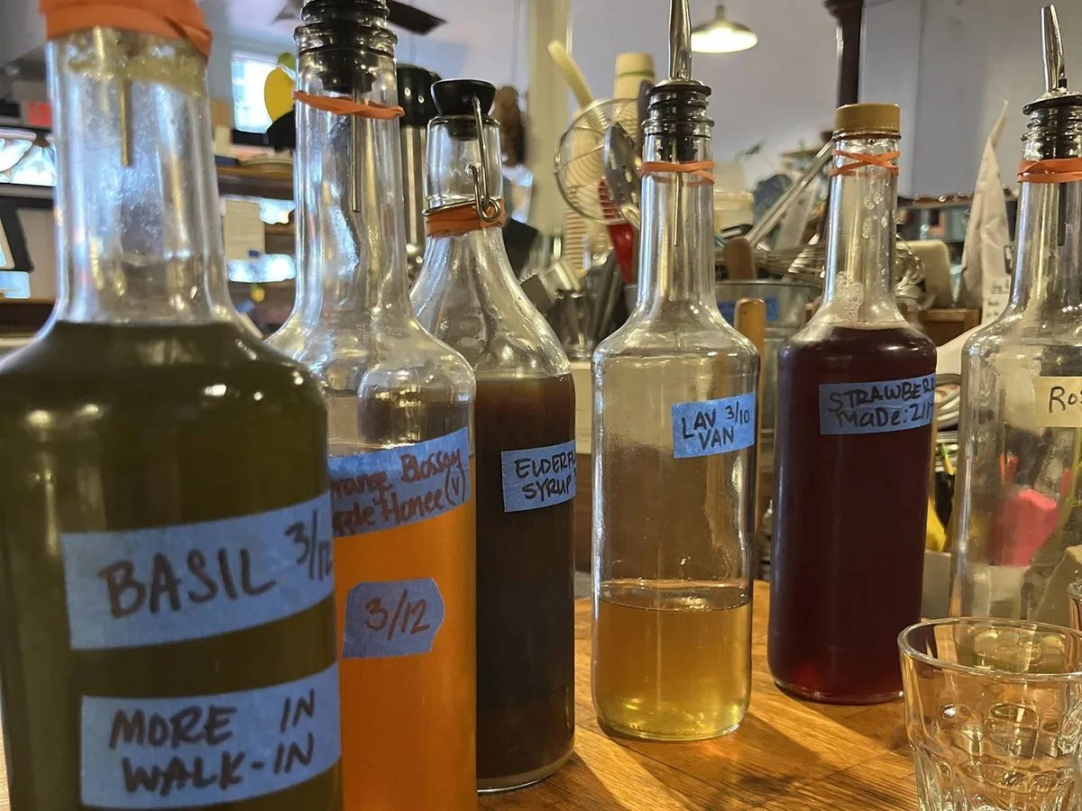 Hand-labeled bottles of CDA house-made syrups — basil, orange blossom honey, elderflower, lavender vanilla and strawberry