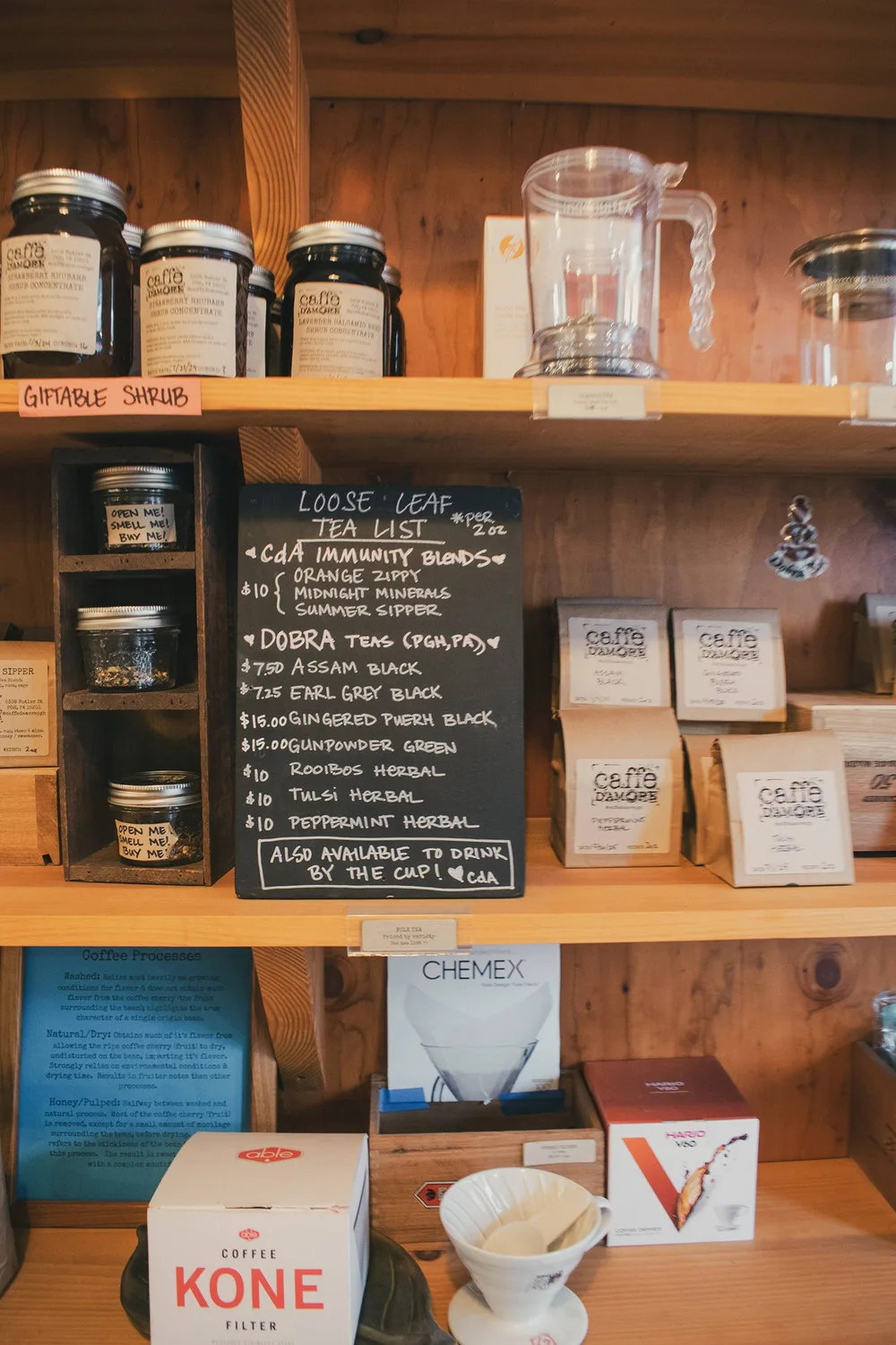 Chalkboard loose-leaf tea list among jars of CDA teas and brew equipment